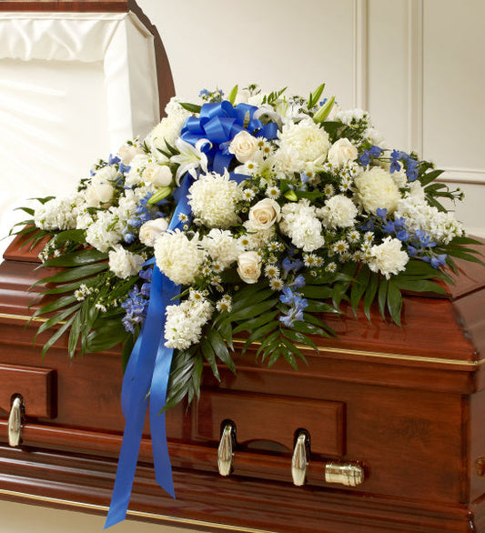 Rose Half Casket in Blue and White, half casket spray with white roses, white carnations, white lilies, blue delphinium, and daisies accented with greenery and a blue ribbon
