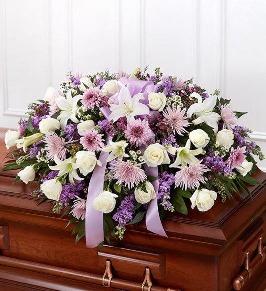 Rose Half Casket in Lavender, half casket spray with white roses, white lilies, pink chrysanthemums, purple stock, and mixed greenery accented with a lavender ribbon