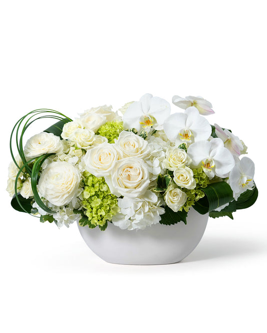 Beautiful arrangement of white roses, orchids, and green hydrangeas in a sleek white vase. Perfect for any elegant occasion.